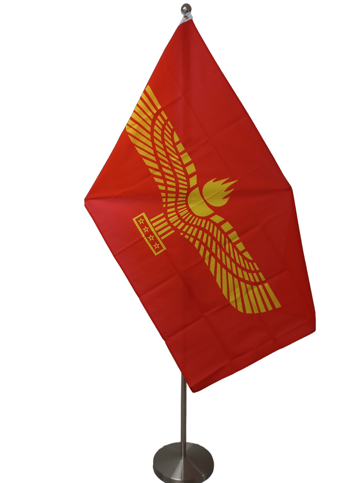 A red flag with a yellow geometric pattern resembling a bird in flight and a symbol below it. On a ceremonial flag pole.