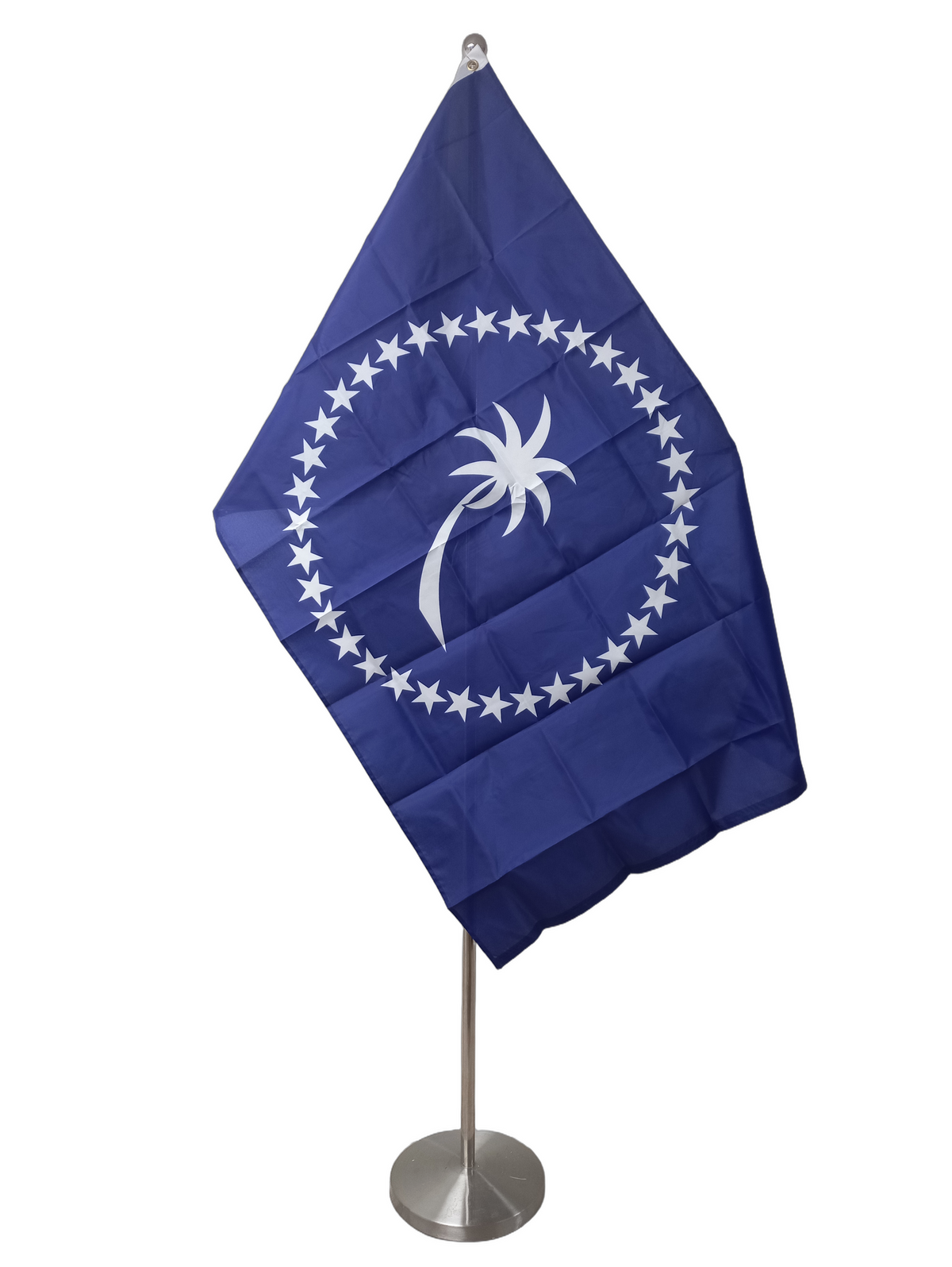 Flag of Chuuk - Micronesia with a blue background and a white emblem featuring a palm tree and stars arranged in a circle. On a ceremonial flag pole.