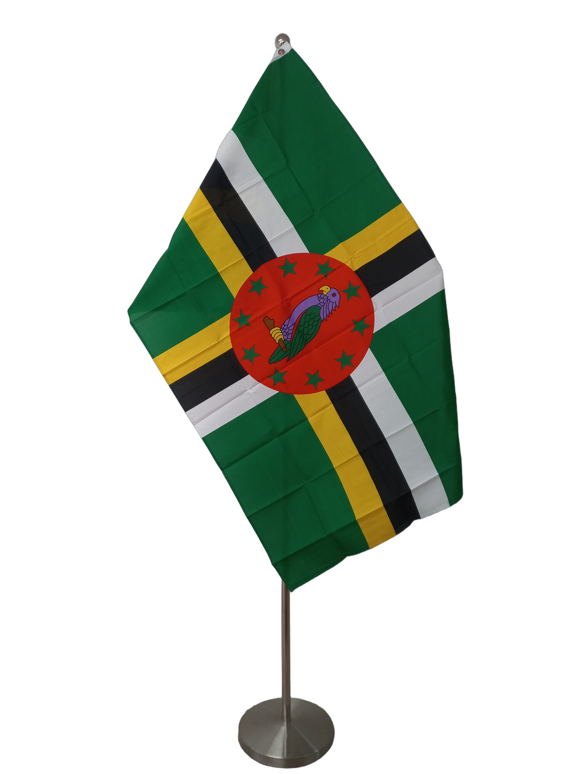 Flag of Dominica, green background with a stylized yellow, black and white cross. On the middle of the cross there is a red circle with 10 green stars and a parrot. On a ceremonial flag pole.