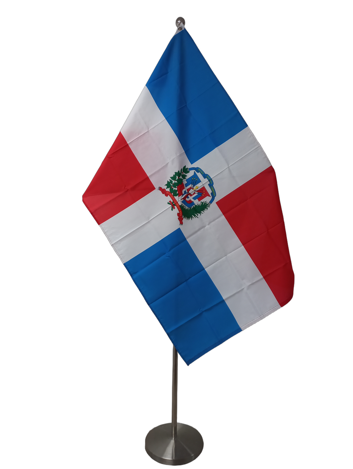 Flag of the Dominican Republic, featuring blue in top left and bottom right and red in top right and bottom left with a white cross that contains a national emblem dividing the colours, and two metal grommets for flying. On a ceremonial flag pole.