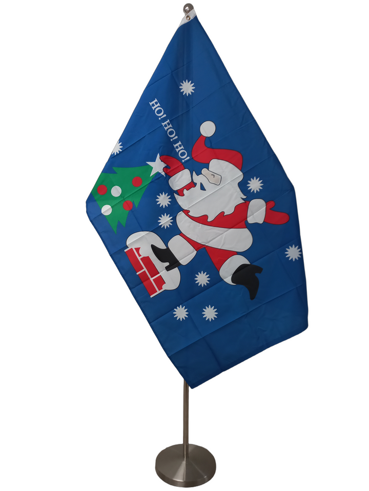 A flag of Santa on a blue background putting a star on a Christmas tree saying 'HO! HO! HO!'. On a ceremonial flag pole.