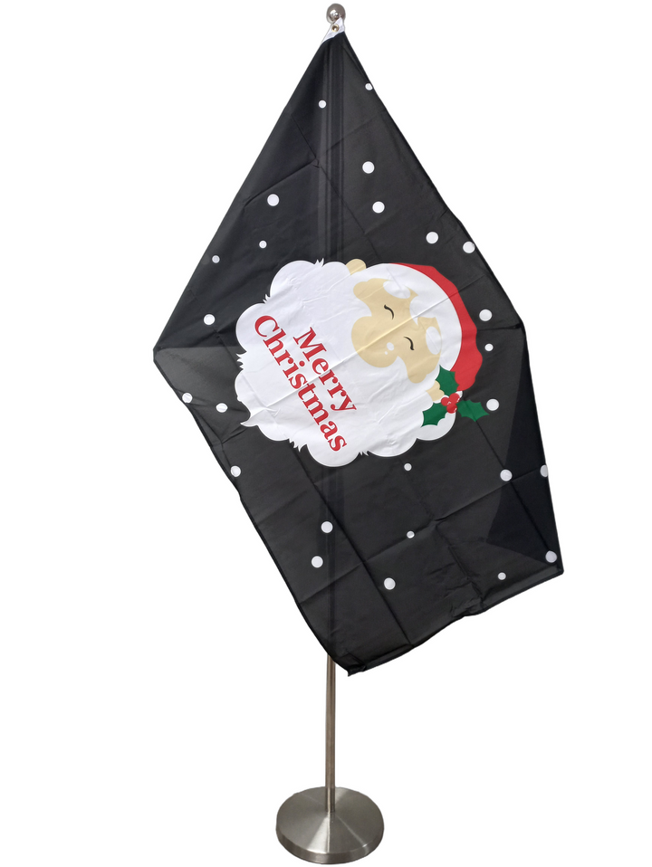 Flag of Santa's face on a black background with white dots. On Santa's beard there is the red text Merry Christmas. On a ceremonial flag pole.